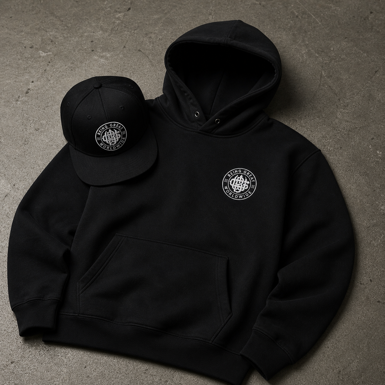 Black hoodie and cap with a logo on a gray surface